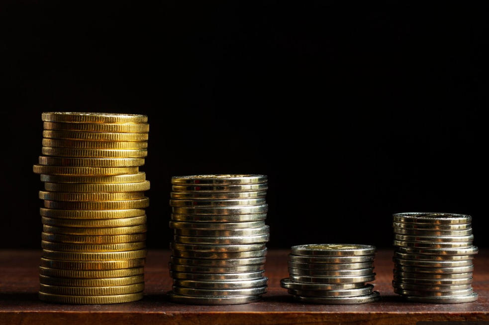 Gold and silver coin stacks show value differences, helping first-time investors decide how to buy gold in Vancouver based on budget and goals.